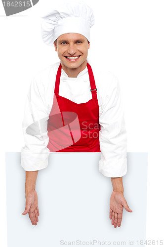 Image of A smiling chef posing behind white billboard