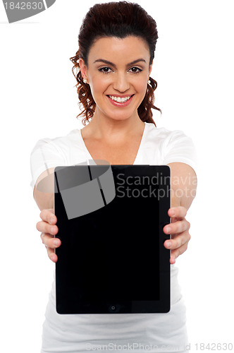 Image of Woman holding tablet device, showing it to camera