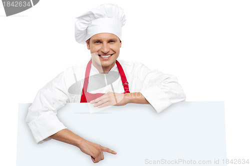 Image of Handsome chef pointing at white billboard