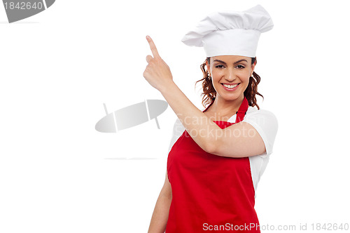 Image of Attractive female chef pointing at copy space