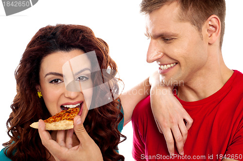 Image of Girl enjoying pizza piece shared by her boyfriend