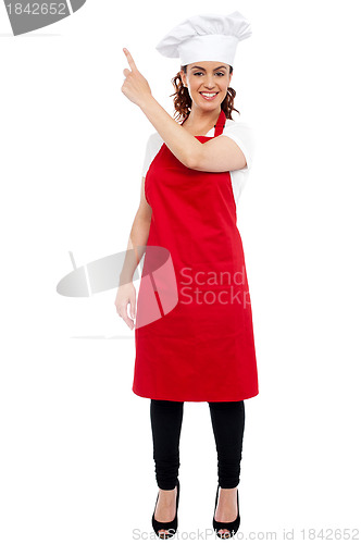 Image of Full length portrait of female chef pointing away