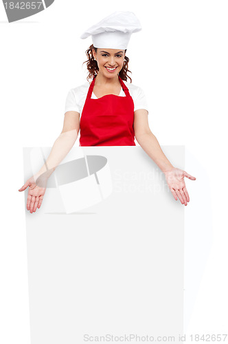 Image of Female chef posing behind blank white billboard