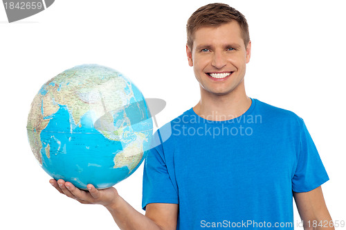 Image of Young cheerful man holding a globe in his hand