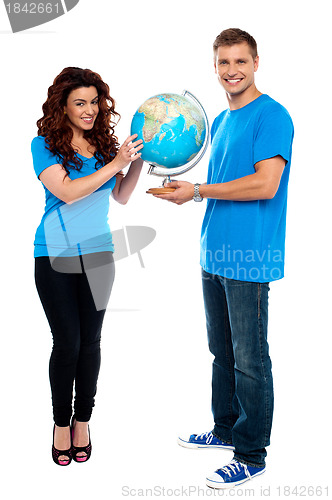 Image of Full length of a couple holding globe over white