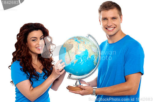 Image of Joyful couple holding globe and smiling at camera