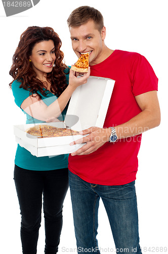 Image of Caring girlfriend making her boyfriend eat pizza