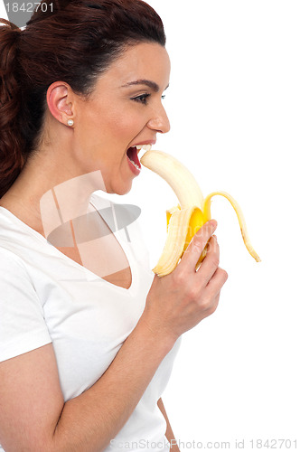 Image of Side view of brunette women eating banana