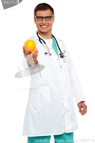 Image of Happy young doctor offering you orange
