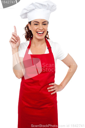 Image of Beautiful smiling female chef indicating upwards