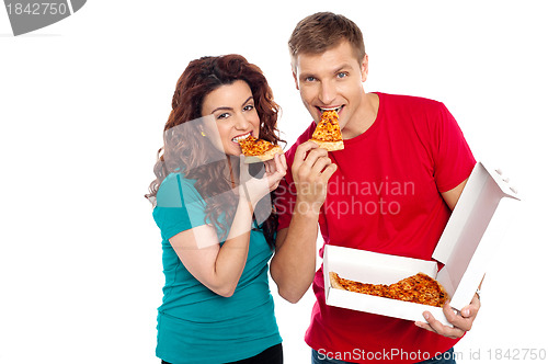 Image of Adorable young couple relishing yummy pizza