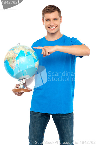 Image of Casual cool guy pointing at rotating globe