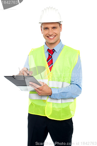 Image of Smiling young construction engineer writing