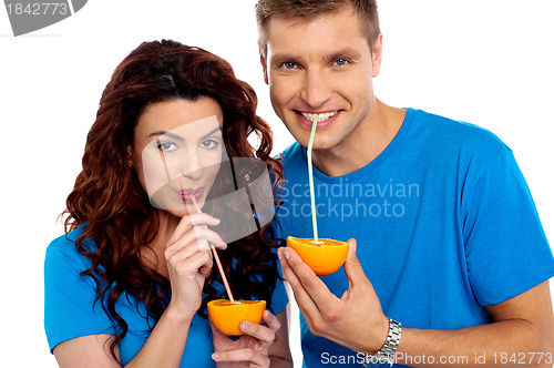 Image of Closeup of couple cuddling and sipping orange juice