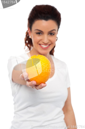 Image of Smiling beautiful woman offering you an orange