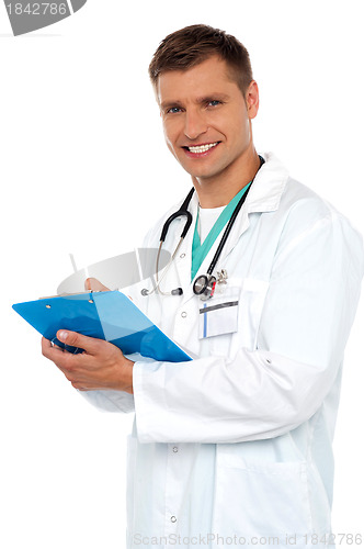 Image of Smiling young doctor writing on clipboard