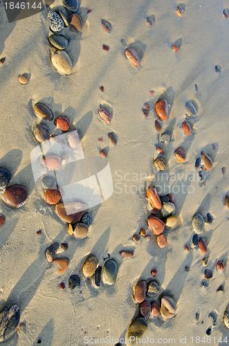 Image of Colorful wet pebbles rubed by waves in sea sand. 