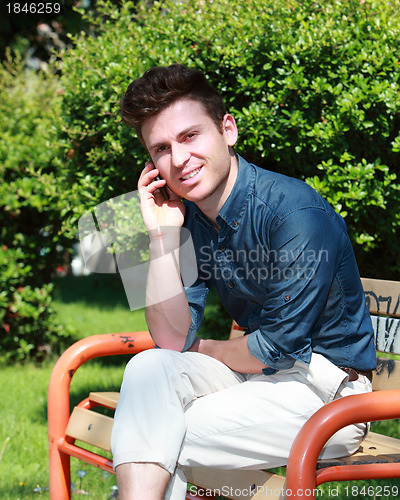 Image of Relaxed handsome man in park calling