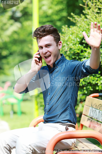 Image of Very happy man at telephone in park