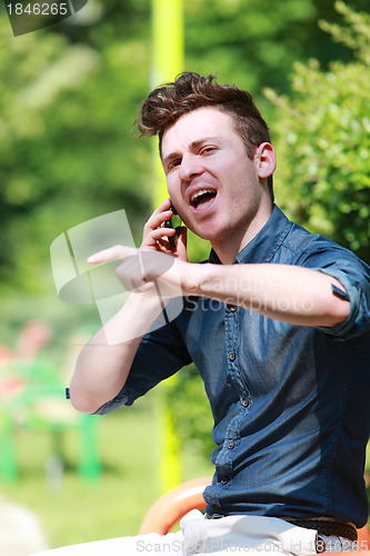Image of Young man in the park talk on telephone