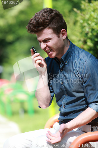 Image of Young man angry on telephone in the park