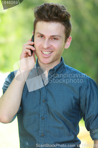 Image of Portrait of handsome man with telephone in park