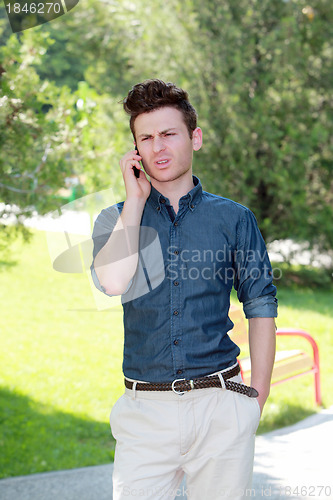 Image of Unhappy man in park on telephone