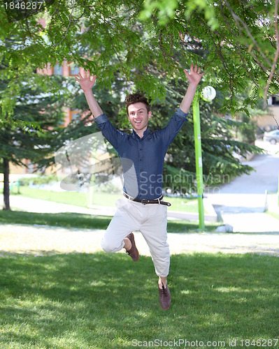 Image of Happy and jumping young man in park