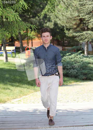 Image of Young man walking in park
