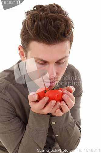 Image of Young man smelling organic tomatoes