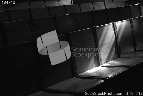 Image of Black and white image of Rows of church pews with stream of ligh