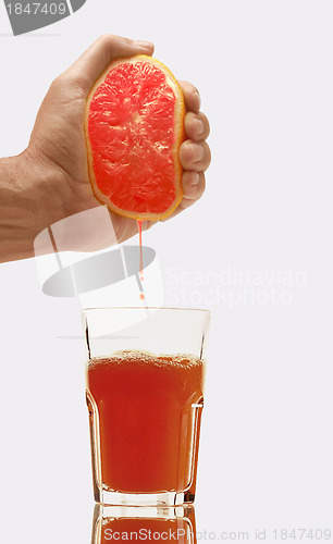 Image of Glass of  grapefruit juice and hand with half of grapefruit