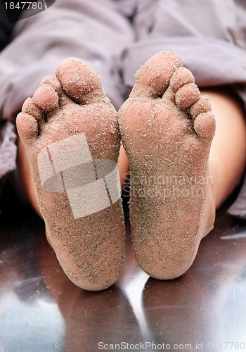 Image of Sandy feet of a children on a play toy of a playground