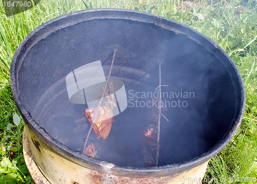 Image of Ecologic fish smoke in smokehouse rusty barrel 