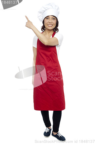 Image of Beautiful female chef pointing at the copy space
