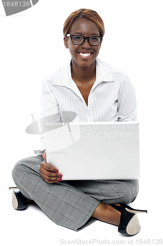 Image of Corporate lady seated on floor working on laptop