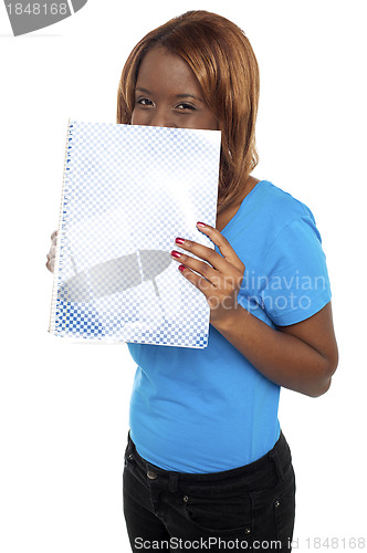 Image of Pretty girl hiding her face through notebook