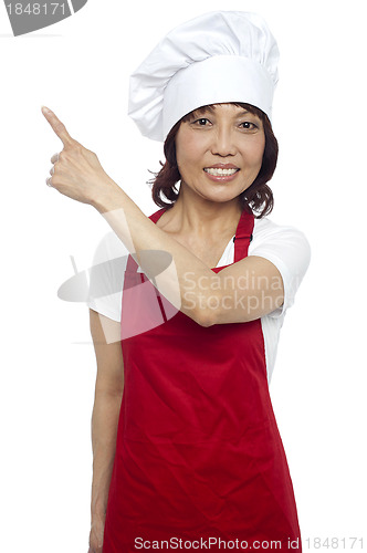 Image of Female chef in uniform pointing away. Copy space concept