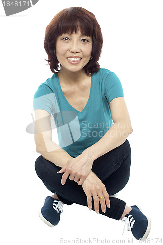 Image of Casual teen girl sitting criss cross on the floor
