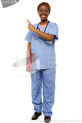 Image of Female doctor pointing at copy space, holding clipboard
