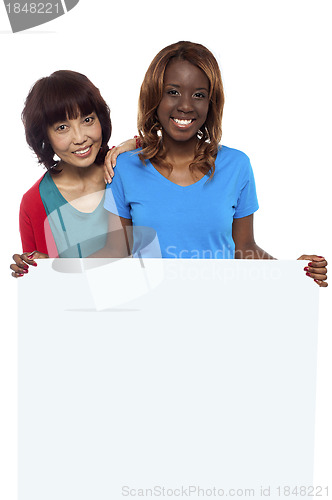 Image of Young ethnic friends behind blank ad board