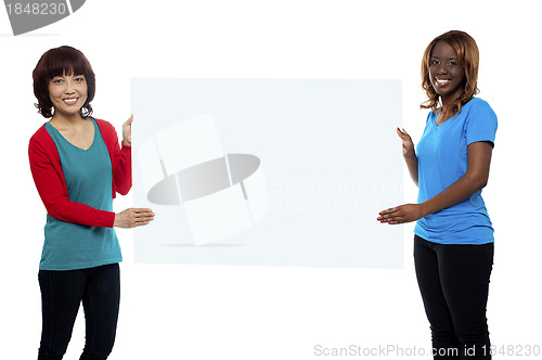 Image of Female marketing executives holding blank billboard