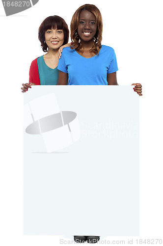 Image of Casual girls standing behind blank whiteboard