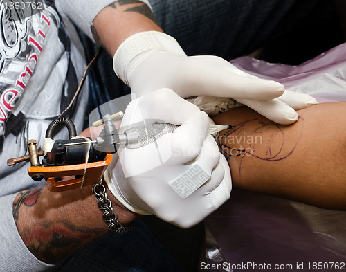 Image of Tattoo artist makes the tattoo on arm