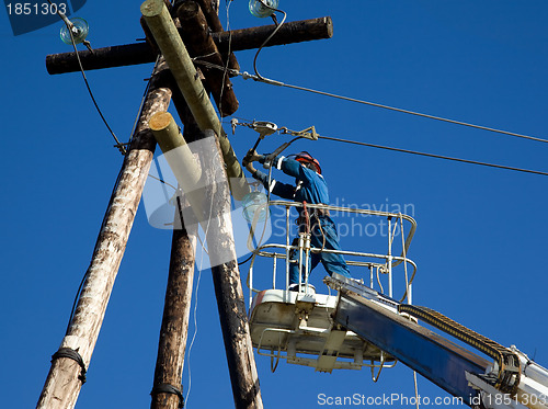 Image of Electrician working on power line pole