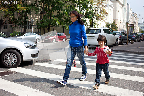 Image of woman with a child going on a pedestrian crossing in the city 