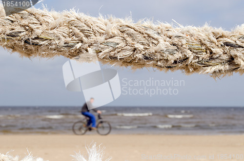 Image of closeup thick rope and cyclist go sea coast beach 