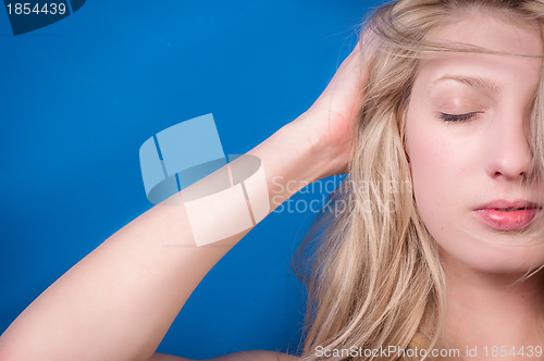 Image of Young blond woman against blue wall