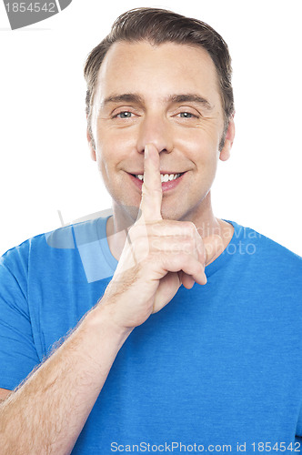 Image of Smiling young man gesturing silence