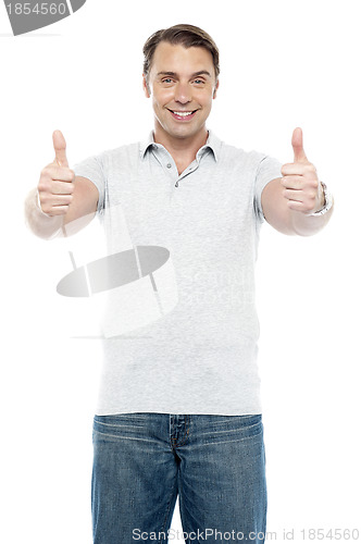 Image of Good looking cheerful man showing double thumbs up